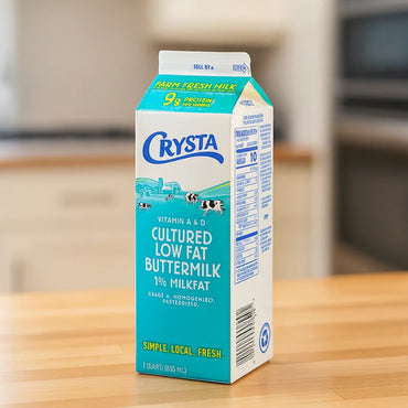 Carton of Crysta Cultured Low Fat Buttermilk on a wooden surface with a blurred kitchen background